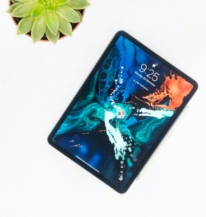 Ipad sitting on a table with a succulent plant.