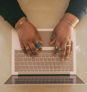 Hands covered in rings and typing on a keypad.