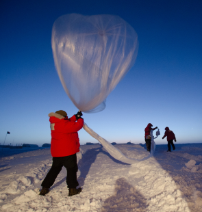 Researcher in a snowy field holding a floatiing plastic structure..