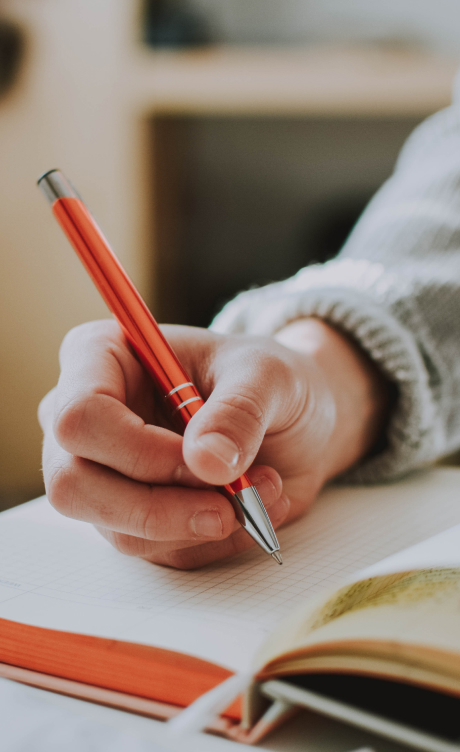 Close up of a hand writing in a journal with a pen.
