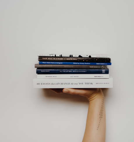 Hand holding a stack of books.